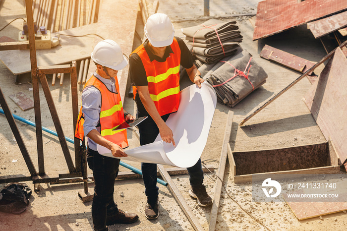 Structural engineer and foreman worker with blueprints discuss, plan inspecting for the outdoors building construction site.