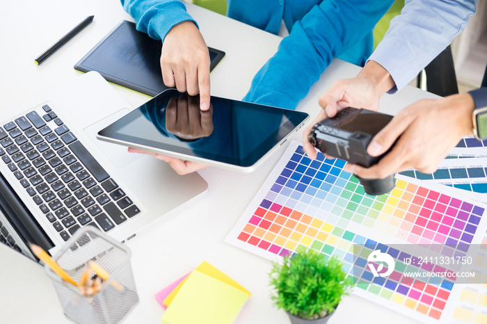 Creative or Interior designers teamwork with pantone swatch and building plans on office desk, architects choosing color samples for design project on a desktop computer