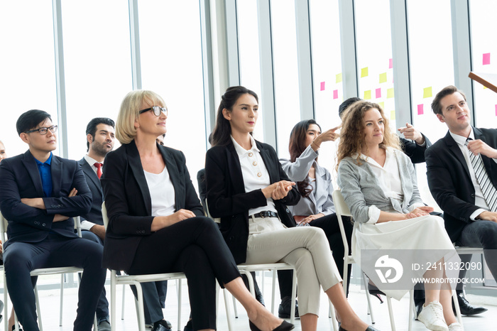 Group of business people meeting in a seminar conference . Audience listening to instructor in employee education training session . Office worker community summit forum with expert speaker .