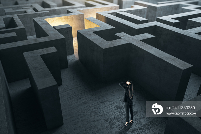 Young businesswoman in suit standing in concerete gray labyrinth.