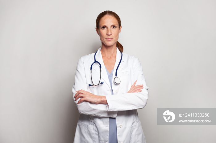 Serious confident medical professional in white lab coat standing against studio wall banner background