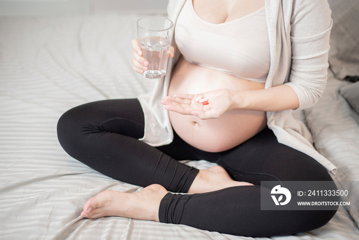 Close up pregnant woman eating vitamin pills