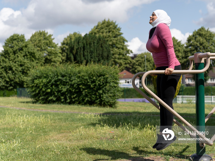 UK,Sutton,Woman in headscarf exercising at park gym