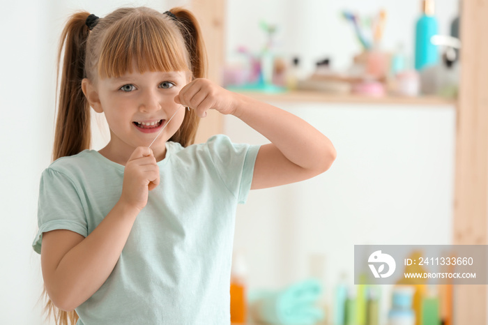 Cute little girl flossing her teeth in bathroom