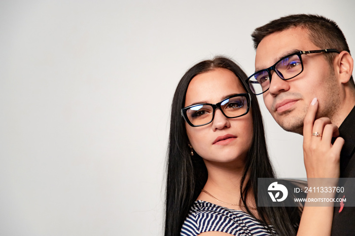 Trendy glasses on a young man and a woman in studio isolated on white wall background. Beautiful couple with modern eyegasses in black frame.