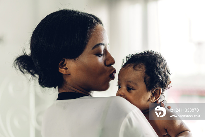 Portrait of enjoy happy love family african american mother playing with adorable little african american baby.Mom touching with cute son moments good time in a white bedroom.Love of black family