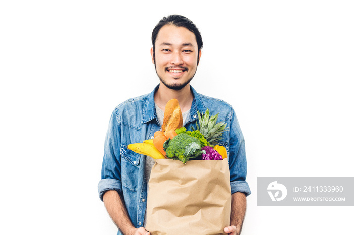 Man holding shopping paper bag with fruit and vegetables on white background