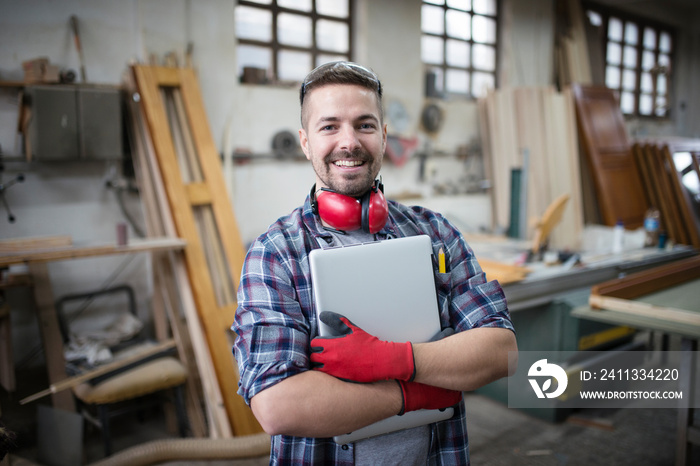 Portrait of experienced architect designer holding laptop computer in workshop.