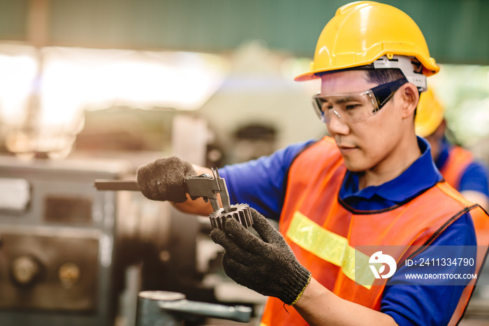 Asian engineer worker using Vernier Caliper to check size for accuracy precision quality control of service machine in factory.