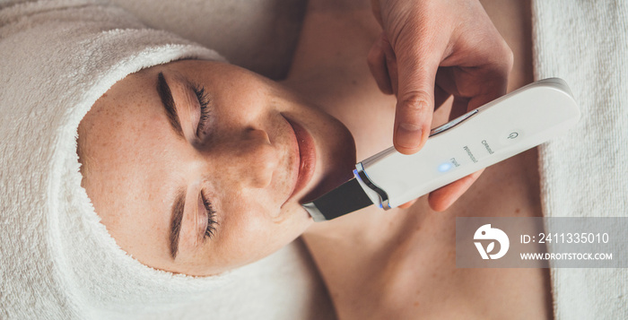 Woman receiving ultrasonic skin cleansing procedure at beauty spa salon. Professional beauty salon. Health care, beauty treatment.