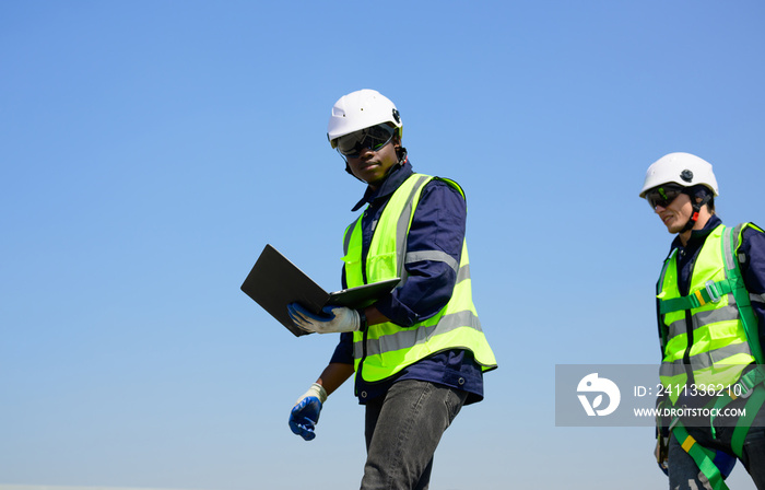 Engineer and technician using laptop checking and operating solar panels system on rooftop of solar cell farm power plant, Renewable energy source for electricity and power,