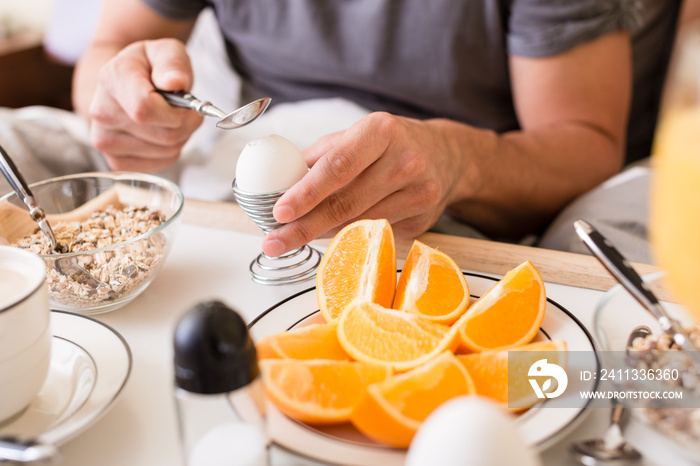 Man cracking open a boiled egg for breakfast