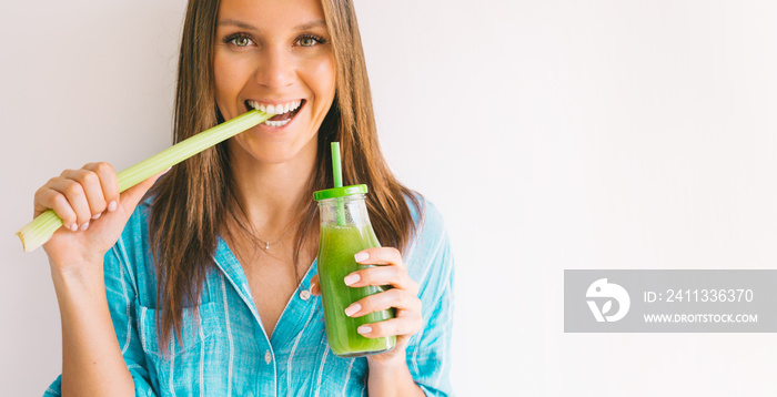 Healthy detox vegan diet. Young beautiful woman eating a stick of green organic celery and drinking fresh homemade celery juice from a glass bottle. Healthy eating and drinking lifestyle. Copy space