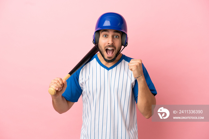 Baseball player with helmet and bat isolated on pink background celebrating a victory in winner position