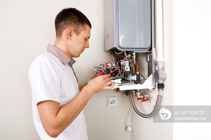 Plumber attaches Trying To Fix the Problem with the Residential Heating Equipment. Repair of a gas boiler