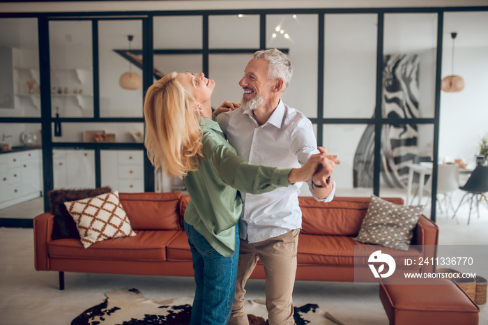 Nice couple dancing in the room and looking happy