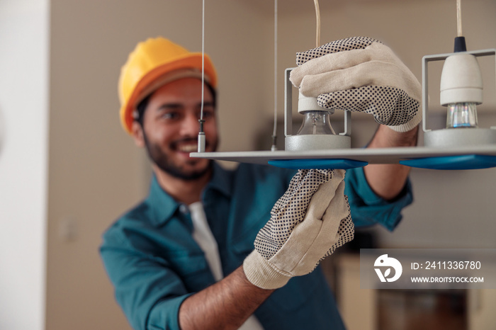 Electrician is installing the light bulbs into the chandelier at home. High quality photo