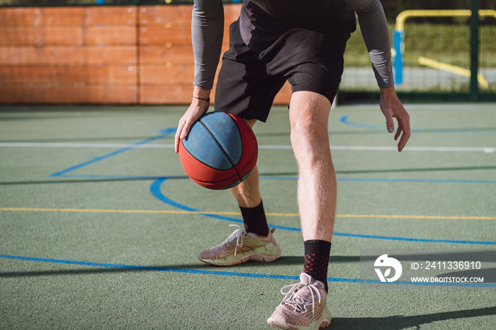 Young talent practices dribbling the basketball under his feet and improves his hand, body and foot coordination. Basketball game. Learning the trick, the deception