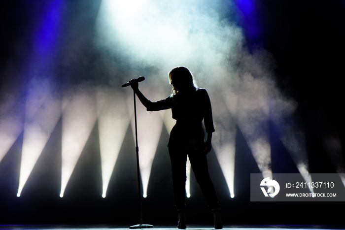 Vocalist singing to microphone. Singer in silhouette