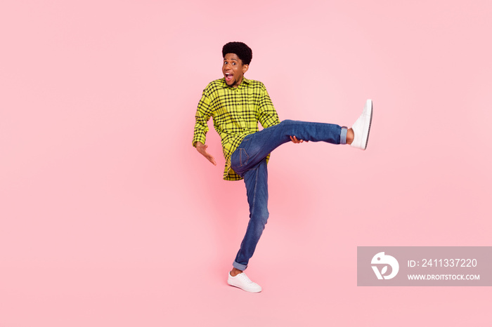 Full size photo of positive happy afro american man raise leg good mood isolated on pink color background