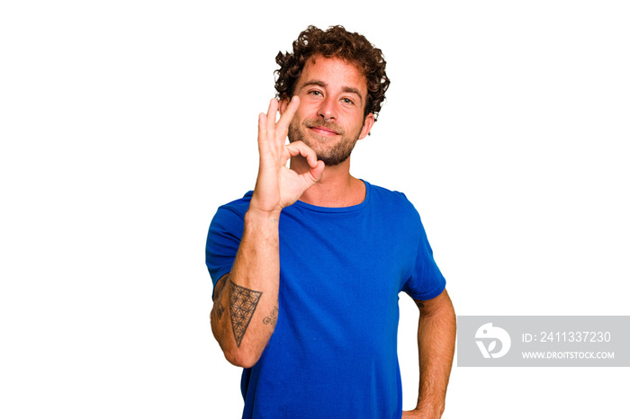 Young caucasian curly hair man isolated Young caucasian man with curly hair isolated winks an eye and holds an okay gesture with hand.