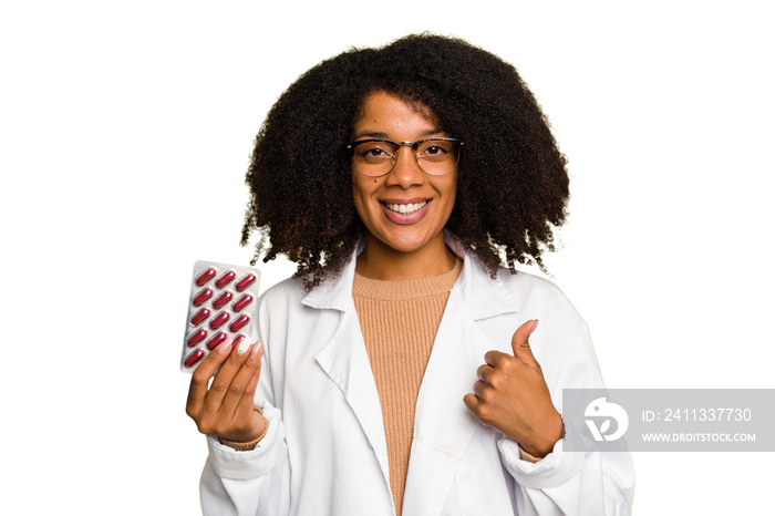 Young pharmacist African American woman holding a tablet of pills isolated smiling and raising thumb up