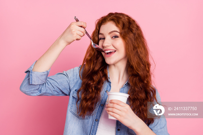 Photo of sweet cute young lady dressed jeans shirt eating yogurt smiling isolated pink color background