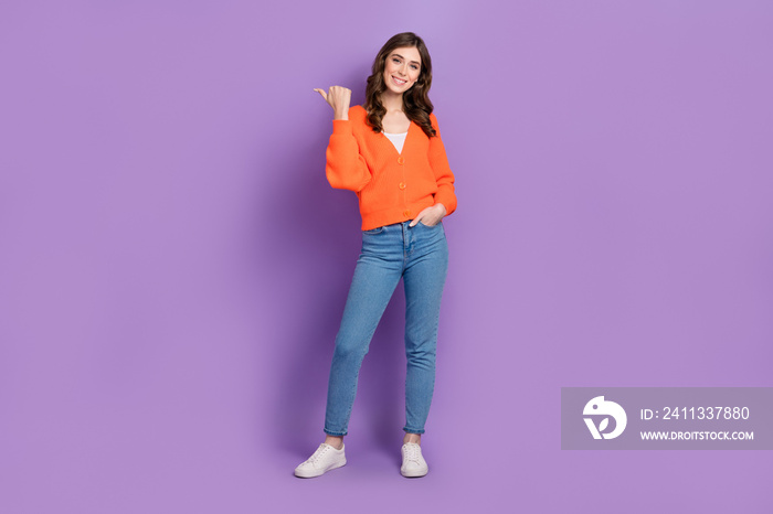 Full length photo cadre of cheerful woman wearing orange cardigan stylish jeans direct thumb mockup useful tips isolated on purple color background