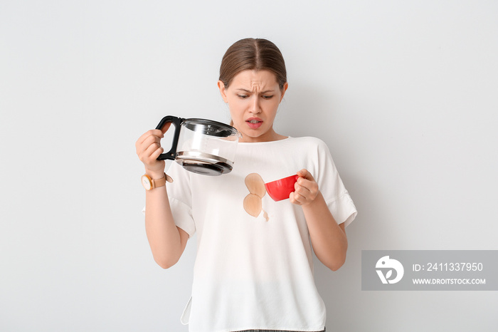 Stressed young woman with coffee stains on her t-shirt on white background