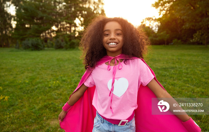 Happy black girl in superhero cape in park