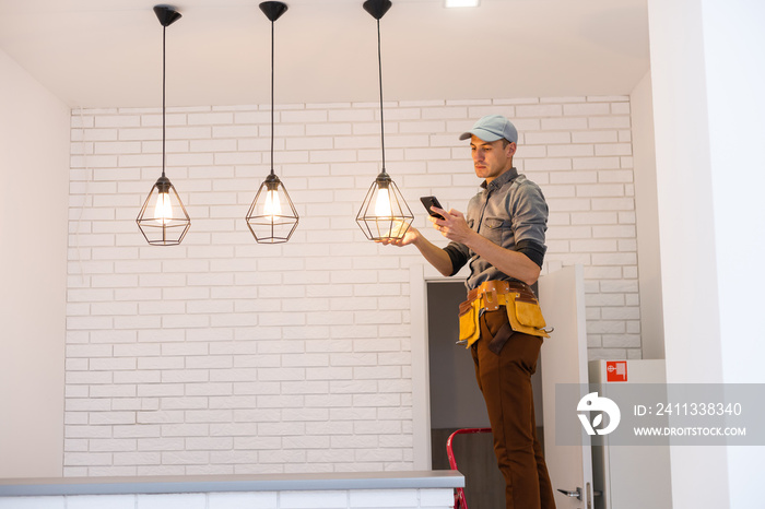 Electrician worker installation electric lamps light inside apartment. Construction decoration concept.