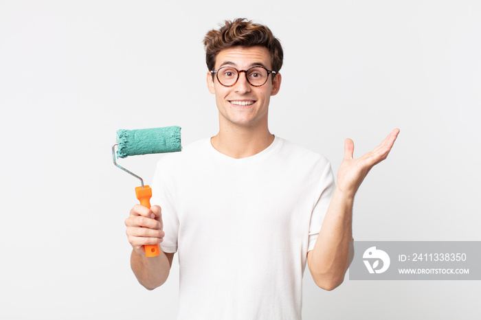 young handsome man feeling happy, surprised realizing a solution or idea and holding a roller paint