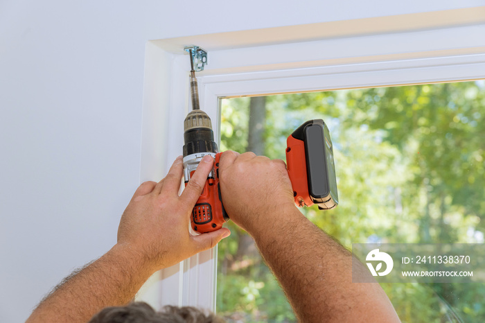 Fastenings are screwed into place by professional technician as blinds are installed on windows of newly constructed house