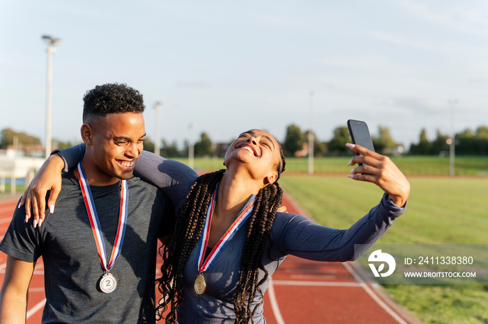 Portrait of male and female athlete celebrating with medals