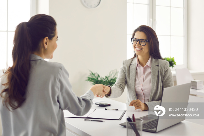 Financing and lending. Handshake of two women of a bank agent and a client after successful signing of documents in the bank office. Manager congratulates the client on a successful transaction.