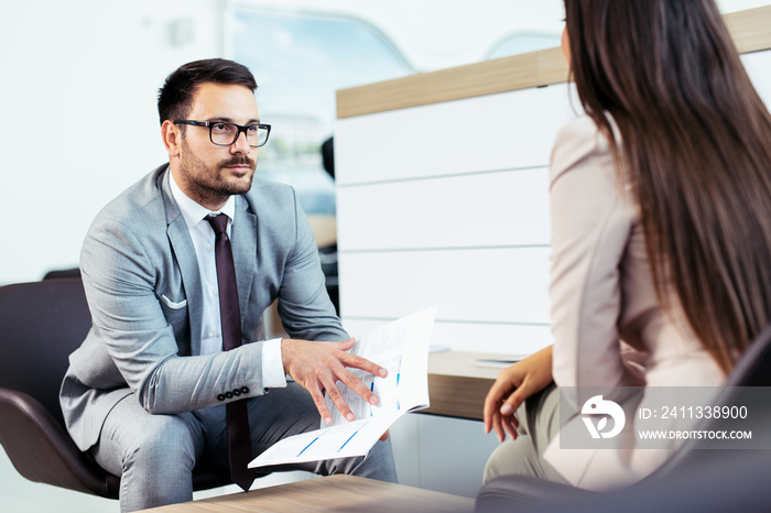 Salesperson selling cars at dealership to buyer