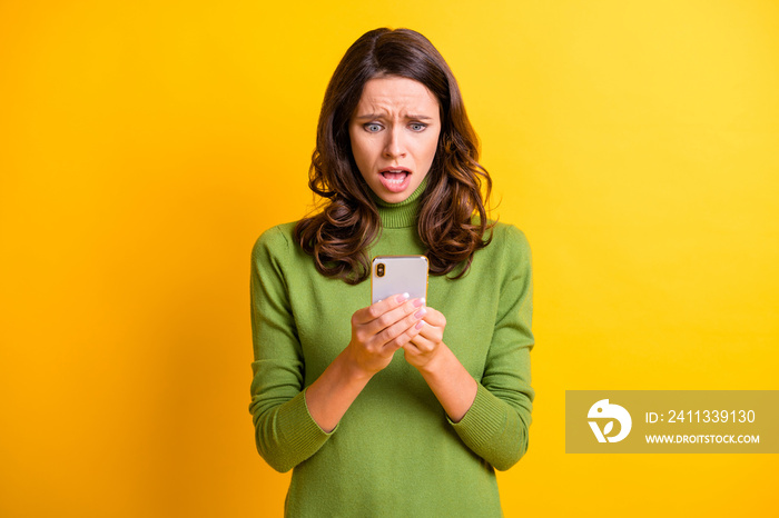 Portrait of young shocked surprised amazed woman hold smartphone red bad review message isolated on yellow color background