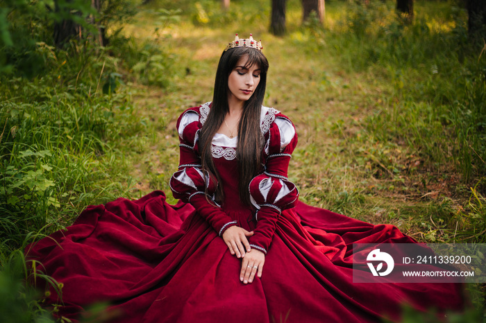 A beautiful girl with black long hair in a medieval, red dress with a crown on her head walks in the forest. Fairy-tale princess. Fantasy