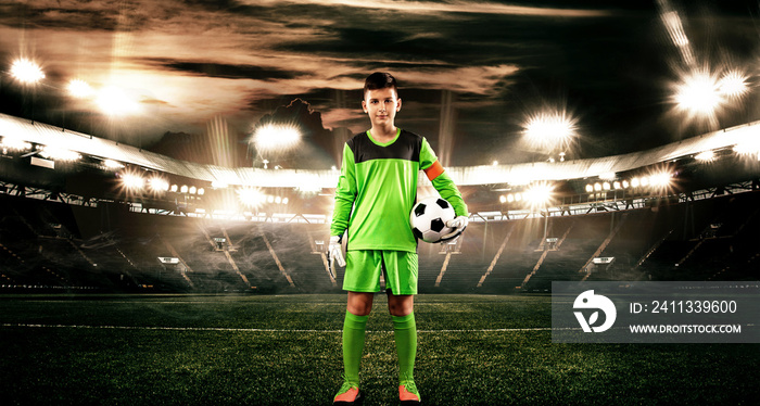 Kids - soccer champion. Boy goalkeeper in football sportswear on stadium with ball. Sport concept.