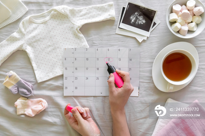 Top vew of expecting pregnant woman notes date of birth on the calendar, pregnancy and birth concept