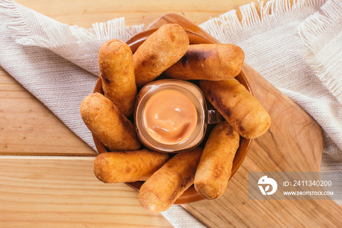 Top view of Latin-American appetizers called Tequeños made of fried corn filled with cheese with a pink sauce