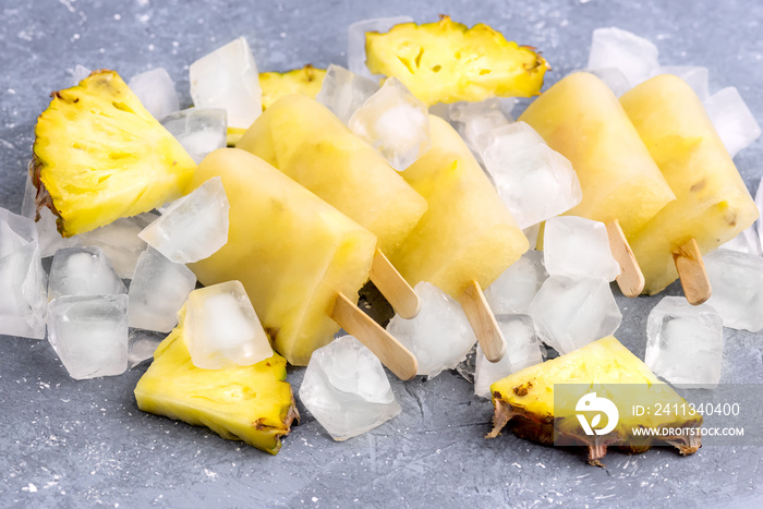 Delicious Homemade Pineapple Popsicles on Ice Cubes Gray Background Summer Food Concept Above Horizontal