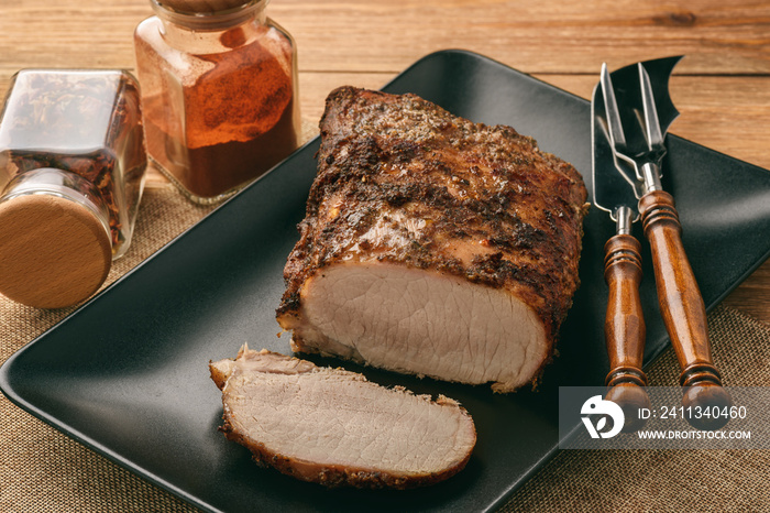 Homemade baked pork tenderloin on wooden background.