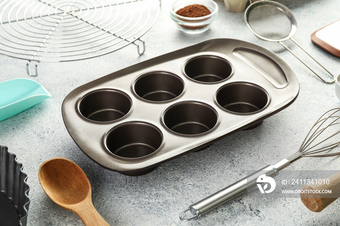 Set of utensils for baking with muffin tray on light background