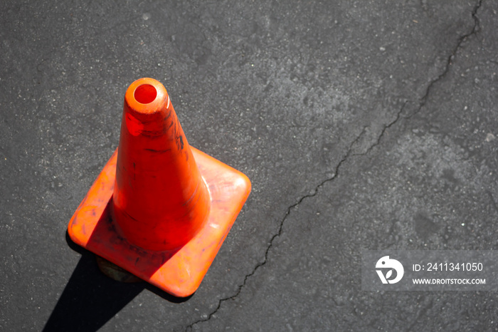 An orange cone on the side of the image, on the pavement