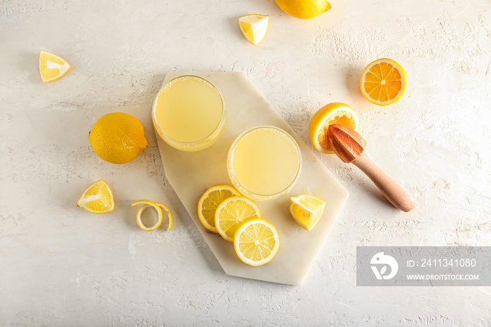 Composition with cut ripe lemons and glasses of fresh juice on light background