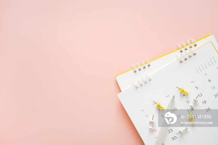 top view of opened white calendar with pen, yellow and white thumbtacks  and sweet pink background