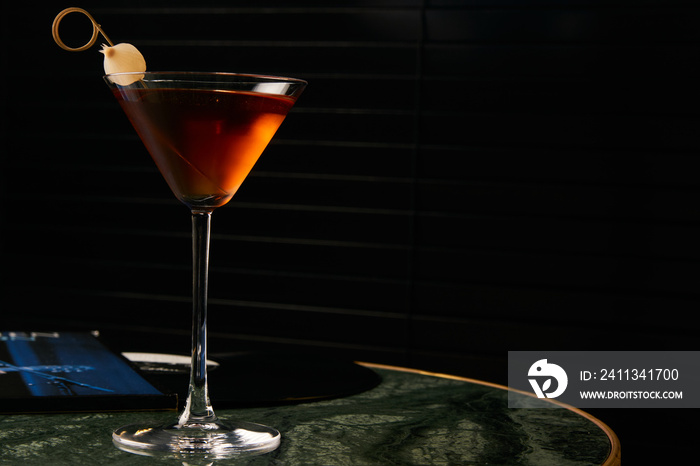 Vinyl Manhattan cocktail on bar table. Freshness Alcoholic beverage drink with whiskey, rosso, rosehip bitter, fernet branca menta ingredients, close-up