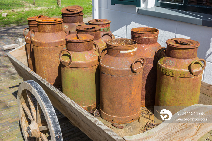 Old rusty milk cans on a wooden cart in historic village Orvelte, Netherlands