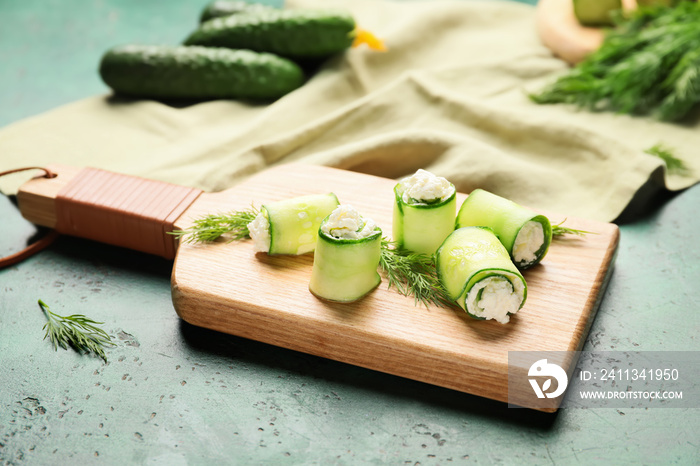 Board with tasty cucumber rolls on table